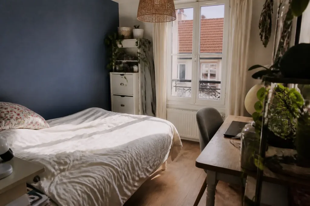 Chambre 10m2 avec lit, bureau, murs bleus et fenêtre ensoleillée