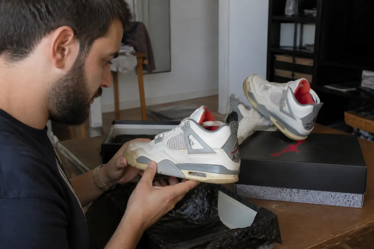 Homme examinant attentivement des sneakers, boîte ouverte à proximité pour vérifier les sneakers.