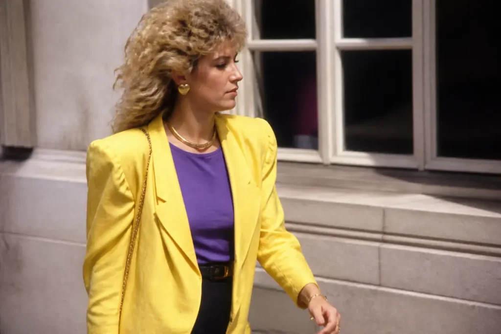 Femme en veste jaune et tenue violette illustrant la mode féminine des années 80