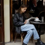 Femme en veste en cuir lisant au café évoquant la mode des années 90