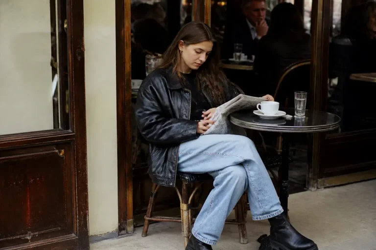 Femme en veste en cuir lisant au café évoquant la mode des années 90