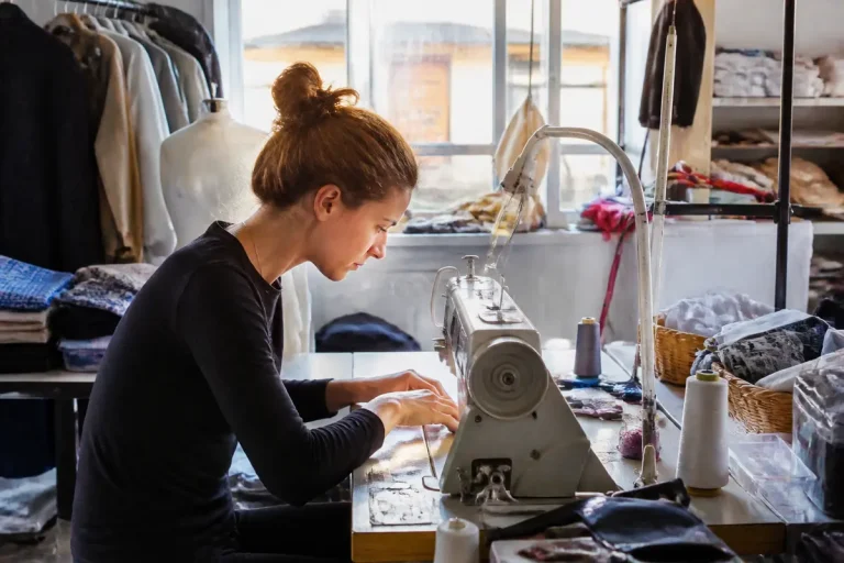 Femme en atelier de couture travaillant sur machine à coudre pour modes et travaux textile