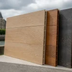 Échantillons de panneaux muraux décoratifs en bois exposés en extérieur devant un bâtiment historique