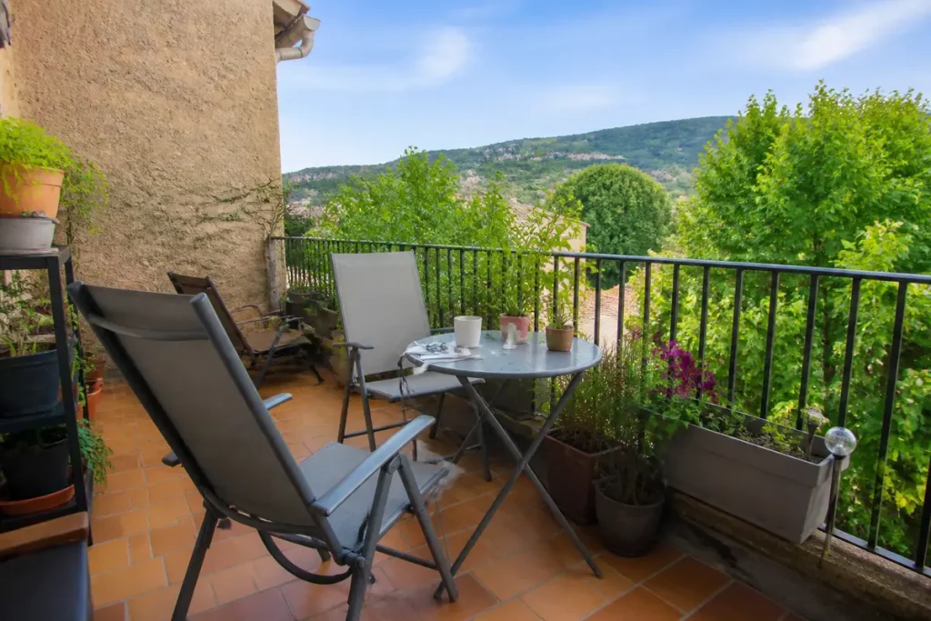 Deux chaises et table sur une petite terrasse cosy avec vue sur collines verdoyantes