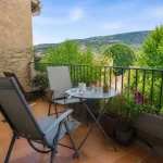 Deux chaises et table sur une petite terrasse cosy avec vue sur collines verdoyantes