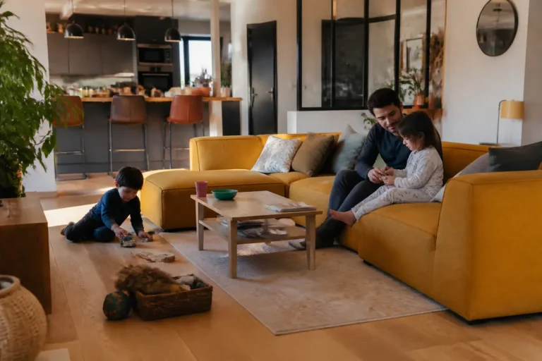 Enfants jouant et adultes discutant dans une pièce de vie moderne et lumineuse