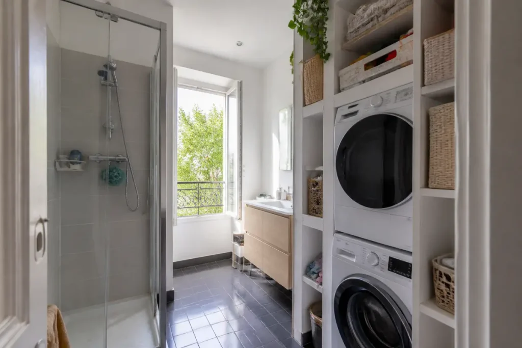 Salle de bain buanderie moderne avec douche, fenêtre ouverte et machines à laver intégrées