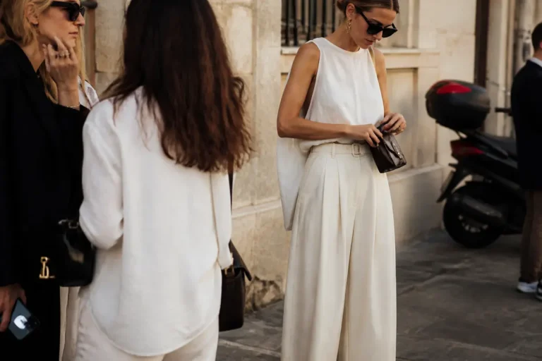 Femme élégante en blanc illustre la tendance de mode avec sac et lunettes noires